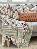 Decorative throw blanket with floral patterns draped over a sofa with matching pillows.