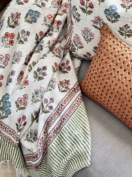 Floral-patterned blanket and woven pillow on a textured surface