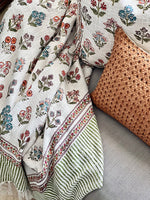 Floral-patterned blanket and woven pillow on a textured surface