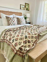 Bedroom with floral-patterned blanket on a bed, wooden bench, and framed pictures.