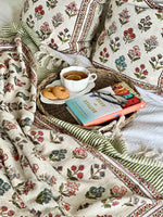 Tray with tea, cookies, and books on a floral-patterned blanket