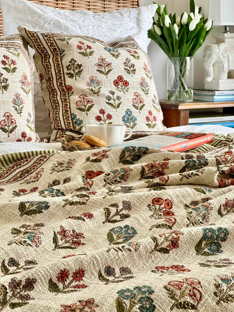 Floral-patterned bedding on a bed with a vase of tulips in the background