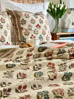 Floral-patterned bedding on a bed with a vase of tulips in the background