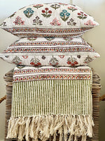 Stack of decorative pillows with floral patterns on a wicker chair.