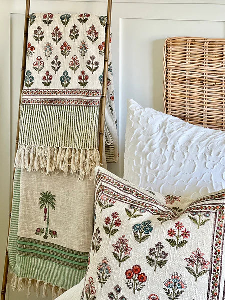 Decorative pillows and blanket with floral patterns on a bed.