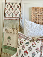 Decorative pillows and blanket with floral patterns on a bed.