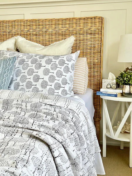Bed with wicker headboard and patterned bedding in a bedroom setting.