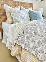 Bed with patterned quilt and pillows in a bedroom setting