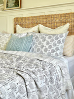 Bed with patterned bedding and pillows in a bedroom setting