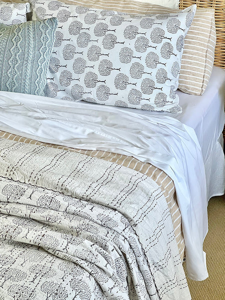 Bed with patterned bedding and pillows on a bed frame.