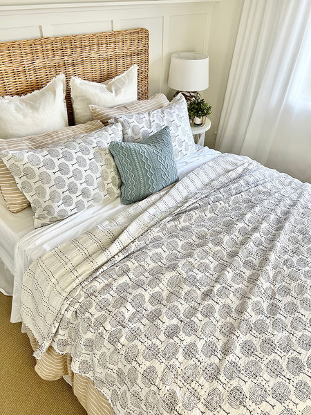 Bed with patterned bedding and pillows in a bedroom setting