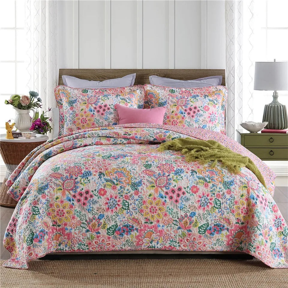 Floral bedding set on a bed in a bedroom with a lamp and table.