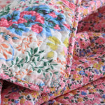 Close-up of a colorful floral quilt with a soft texture.