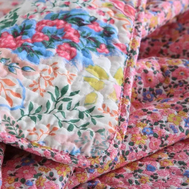 Close-up of a colorful floral quilt with a soft texture.