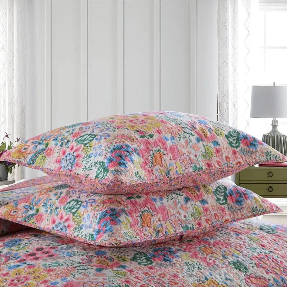 Floral bedding set on a bed with a white wall and lamp in the background