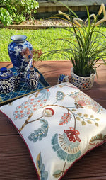 Decorative pillow with floral pattern on a wooden surface outdoors