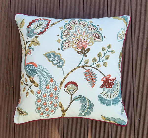 Decorative pillow with floral and peacock design on a wooden surface