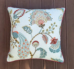 Decorative pillow with floral and peacock design on a wooden surface