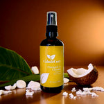 Bottle of Calm & Cozy room spray with a coconut and pineapple on a wooden surface