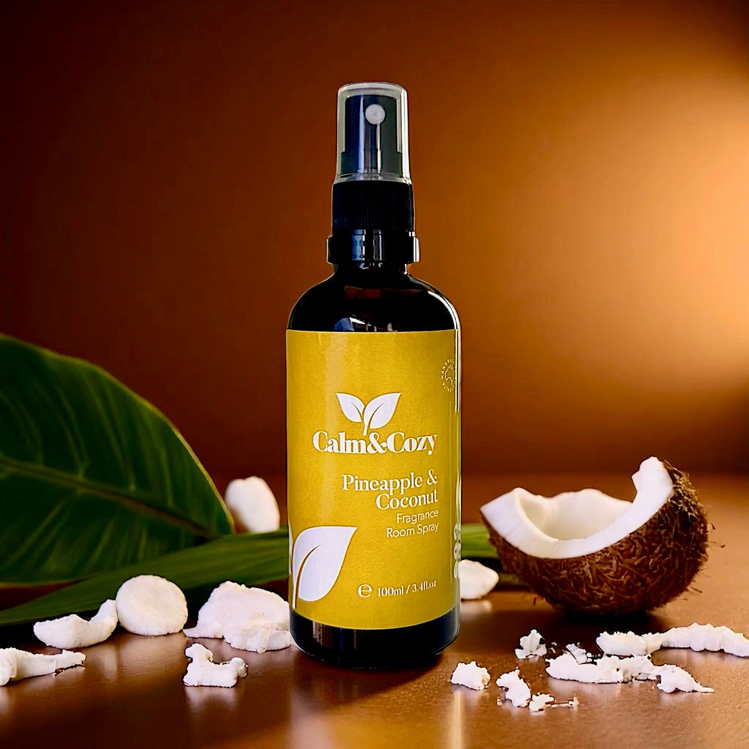 Bottle of Calm & Cozy room spray with a coconut and pineapple on a wooden surface