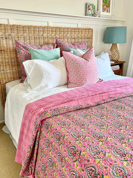 Bed with pink paisley comforter and colorful pillows in a bedroom setting.