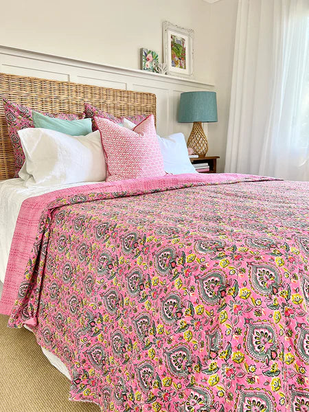 Bed with pink paisley comforter and colorful pillows in a bedroom setting.