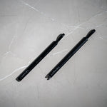 Two black pens with 'LUMAIR' branding on a gray marble surface