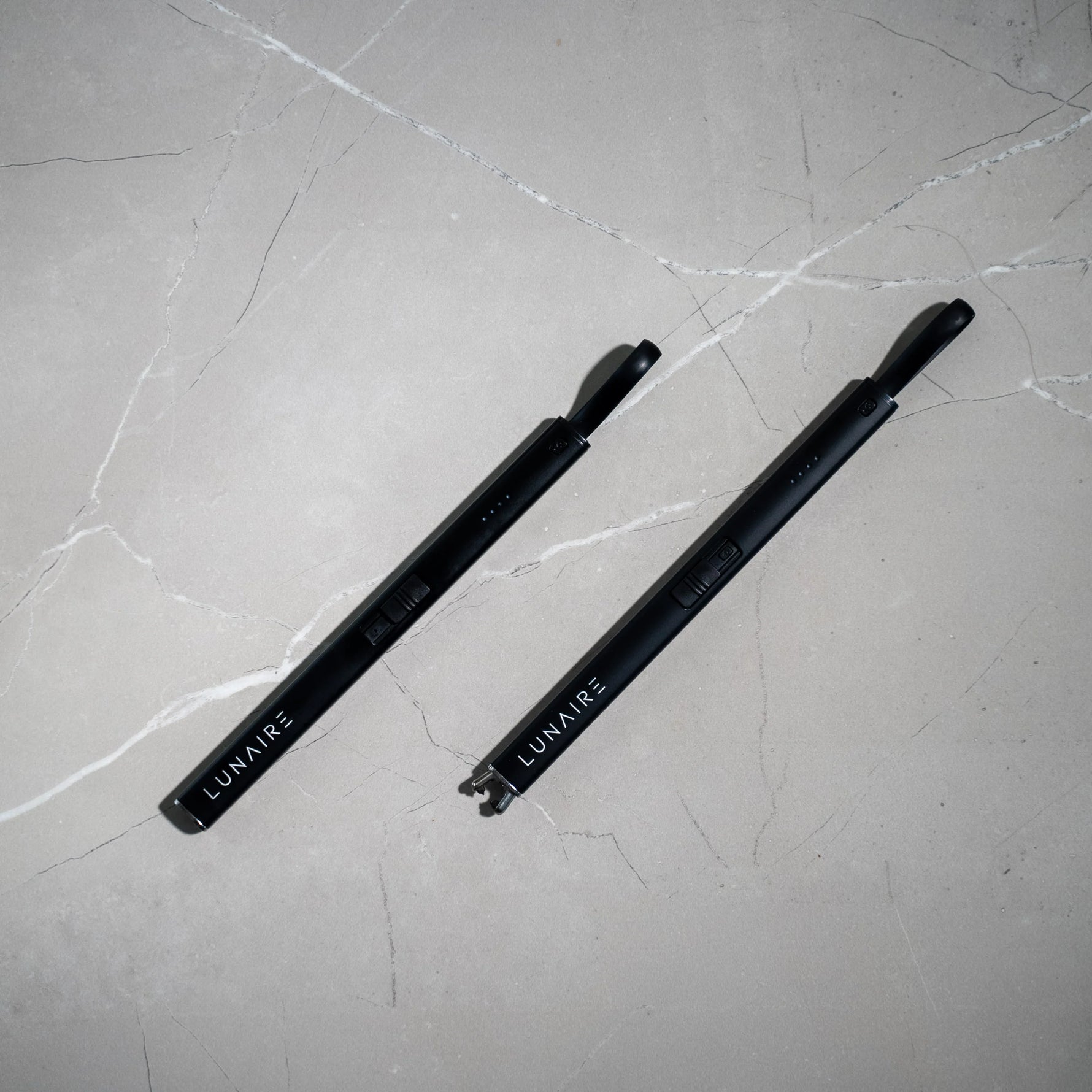 Two black pens with 'LUMAIR' branding on a gray marble surface
