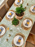 Dining table set with plates, napkins, and decorative items on a floral tablecloth.