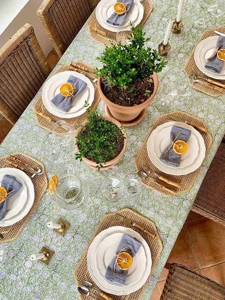 Dining table set with plates, napkins, and decorative items on a floral tablecloth.