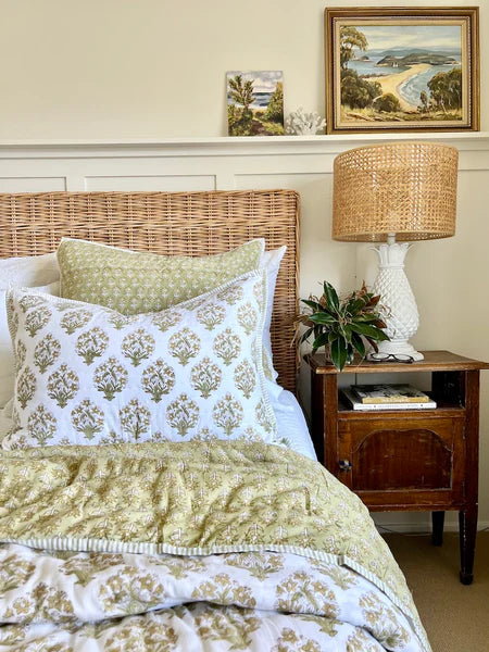 Bedroom with wicker headboard, patterned bedding, and wooden nightstand.