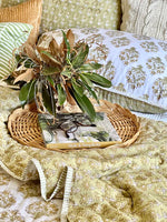 Decorative arrangement with greenery on a wicker tray over a patterned blanket