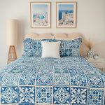 Bedroom with blue and white patterned bedding, framed artwork, and decorative items.