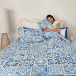 Woman lying on a bed with blue and white patterned bedding