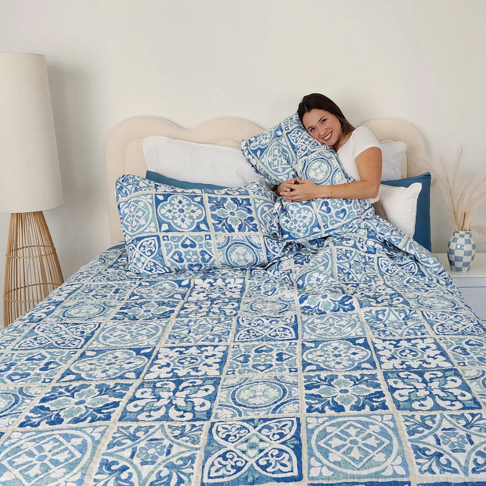 Woman lying on a bed with blue and white patterned bedding