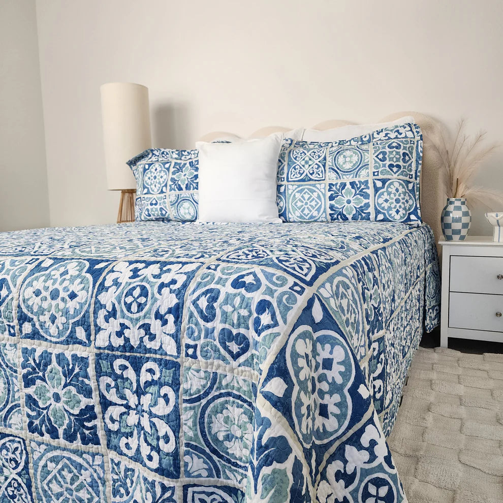 Bed with blue and white patterned bedding in a bedroom setting.
