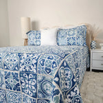Bed with blue and white patterned bedding in a bedroom setting.