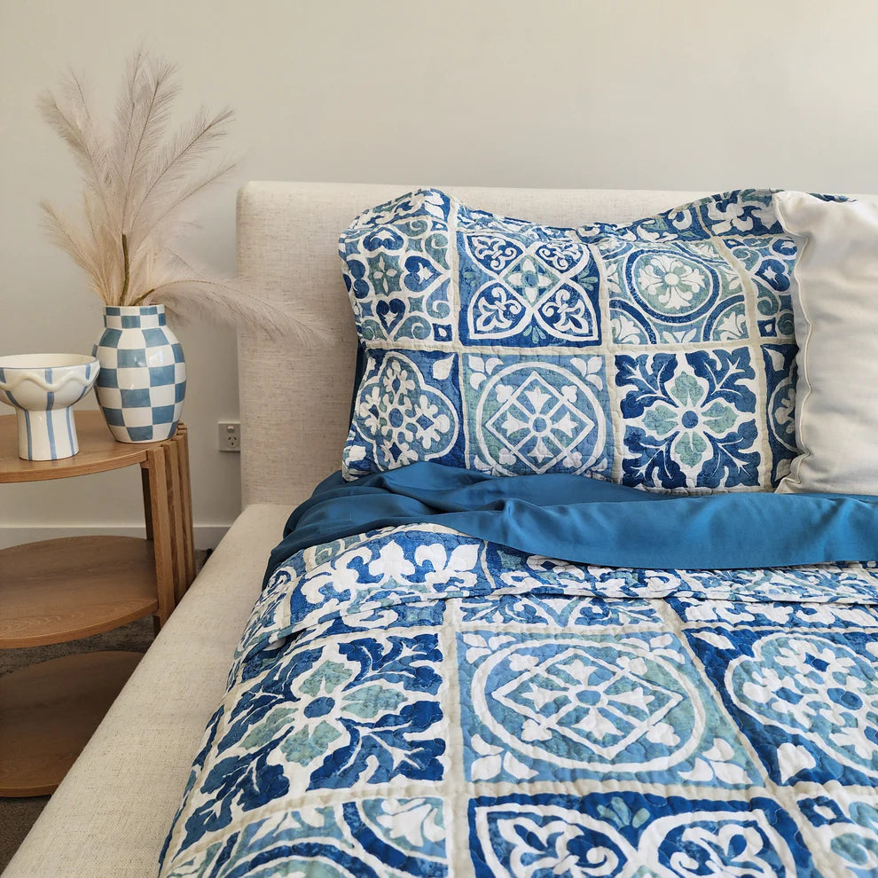 Bed with blue and white patterned bedding in a bedroom setting.