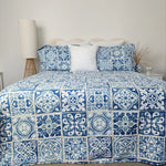 Bed with blue and white patterned bedding in a bedroom setting.