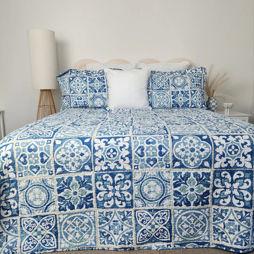 Bed with blue and white patterned bedding in a bedroom setting.