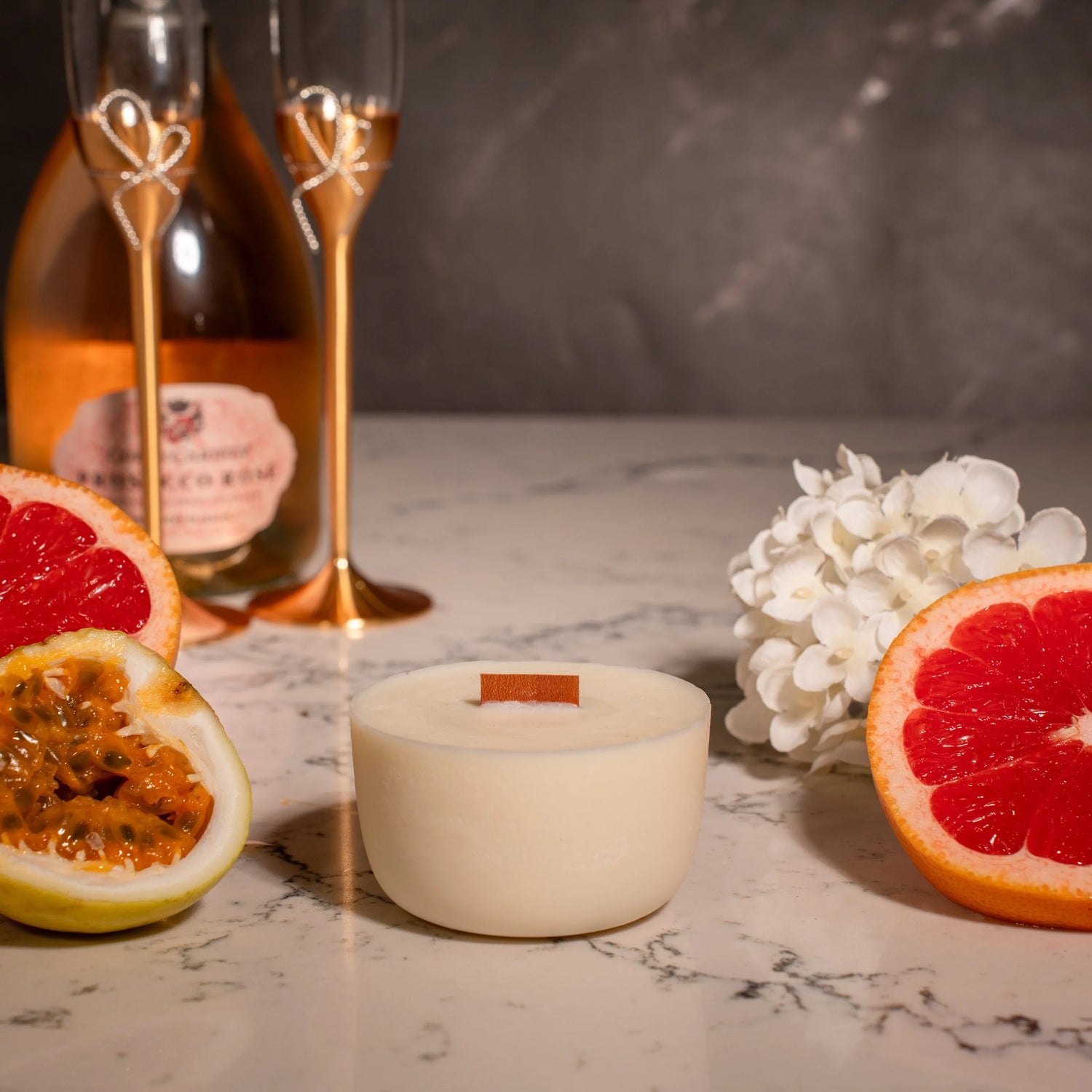 Candle with grapefruit and champagne on a marble surface
