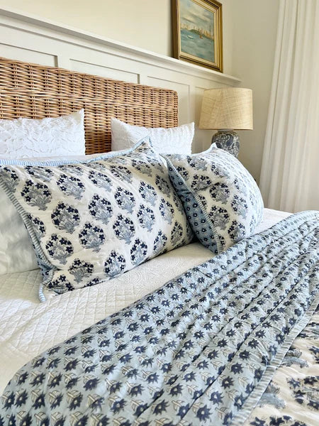 Bed with floral-patterned bedding and wicker headboard in a bedroom setting.