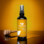 Bottle of 'Calm & Cozy' Spiced Sandalwood & Honey product on a reflective surface with a wooden honey dipper.