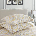 Patterned bedding set on a bed with a neutral headboard and lamp in the background.