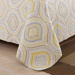 Patterned quilt on a bed with wooden floor and brown rug