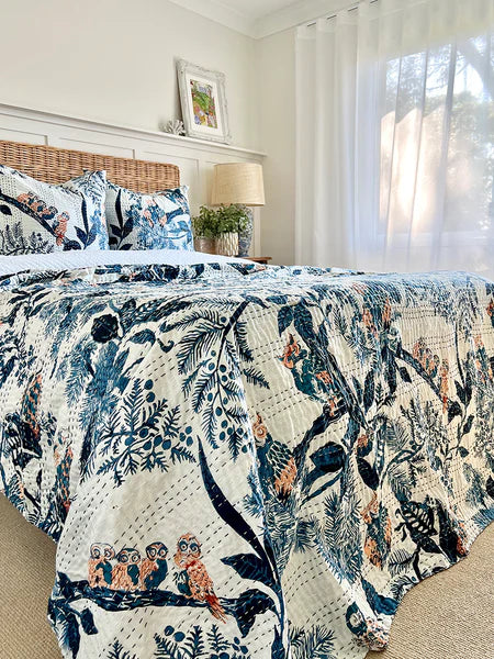 Bed with floral and nature-themed quilt in a bright bedroom