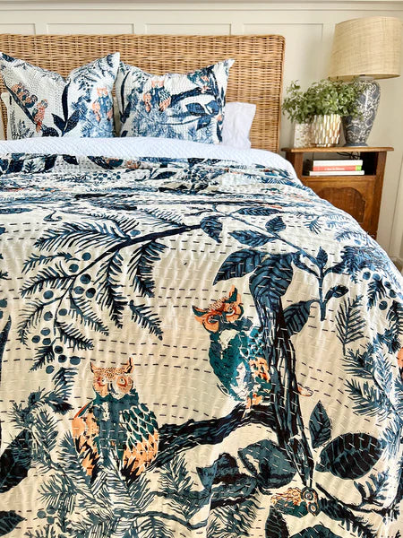 Bed with floral and animal patterned bedding, wicker headboard, and wooden nightstand.