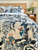 Bed with floral and animal patterned bedding, wicker headboard, and wooden nightstand.