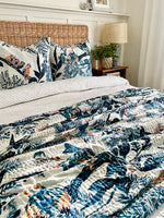 Bed with floral-patterned comforter and pillows in a bedroom setting.