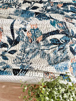 Floral-patterned quilt on a bed with a plant in the foreground